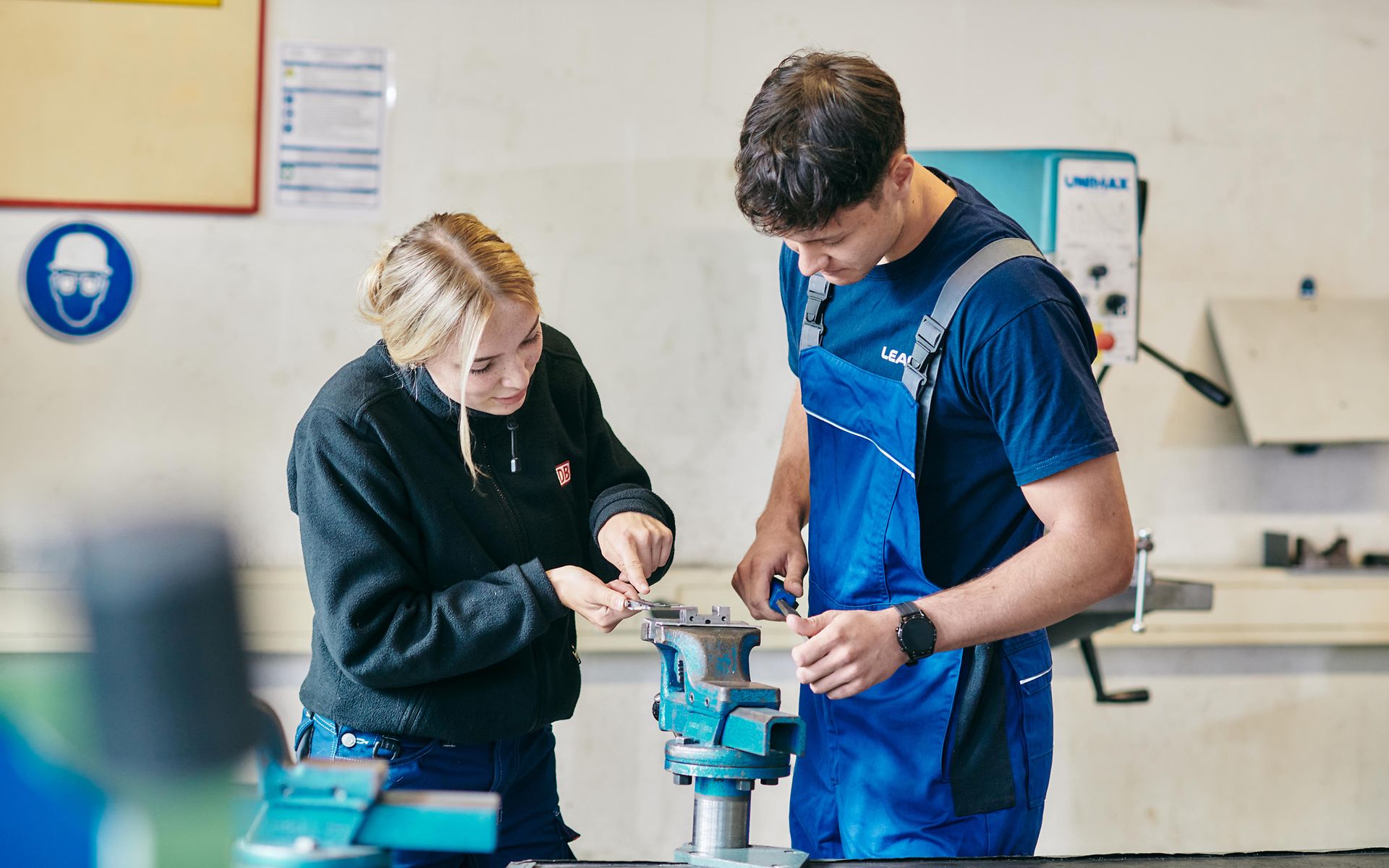 Junge Frau und junger Mann am Schraubstock