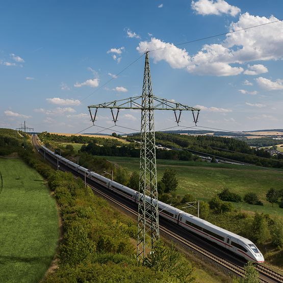 Bahnstrommast in grüner Landschaft mit ICE 4