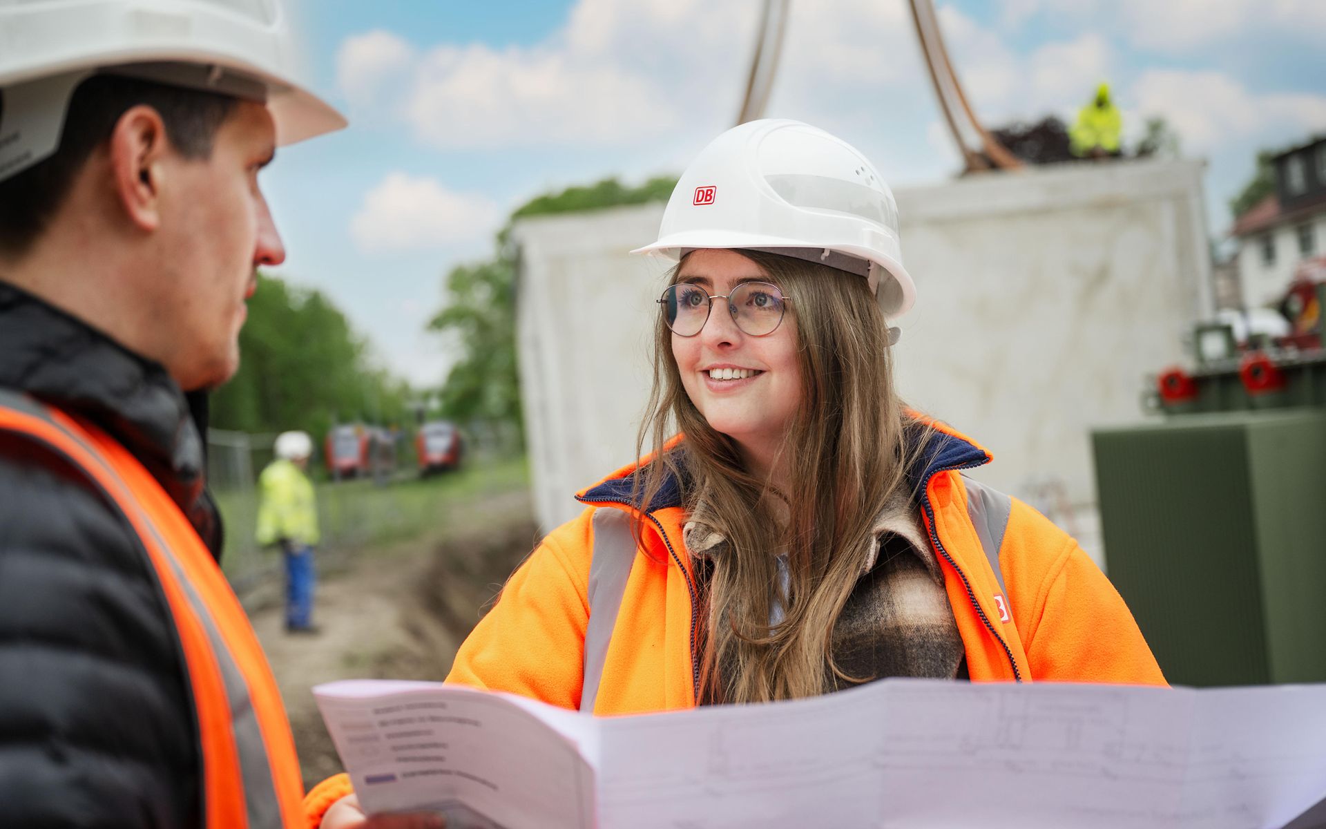 Frau mit Helm im Gespräch auf Baustelle