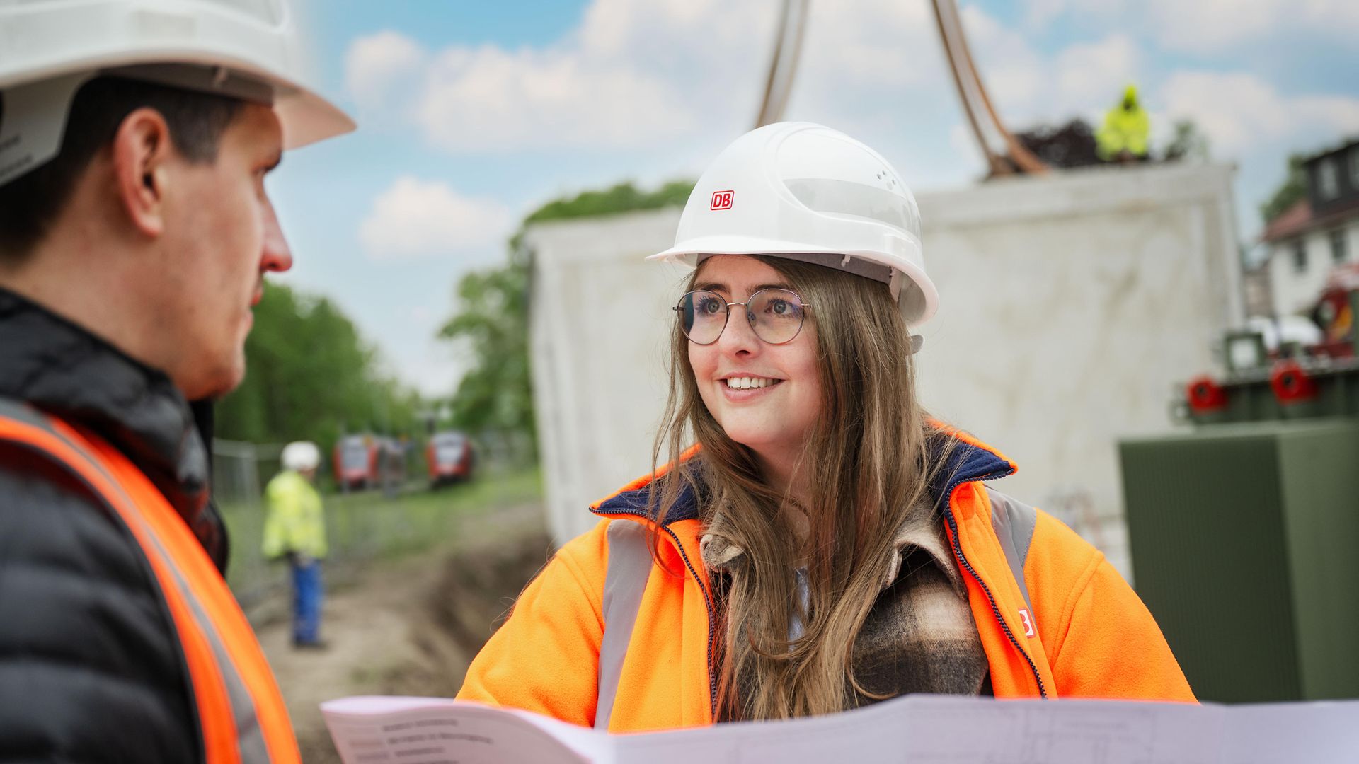 Frau mit Helm im Gespräch auf Baustelle
