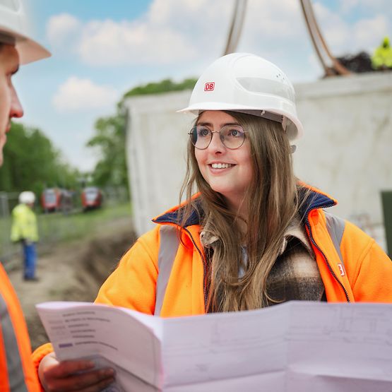 Frau mit Helm im Gespräch auf Baustelle