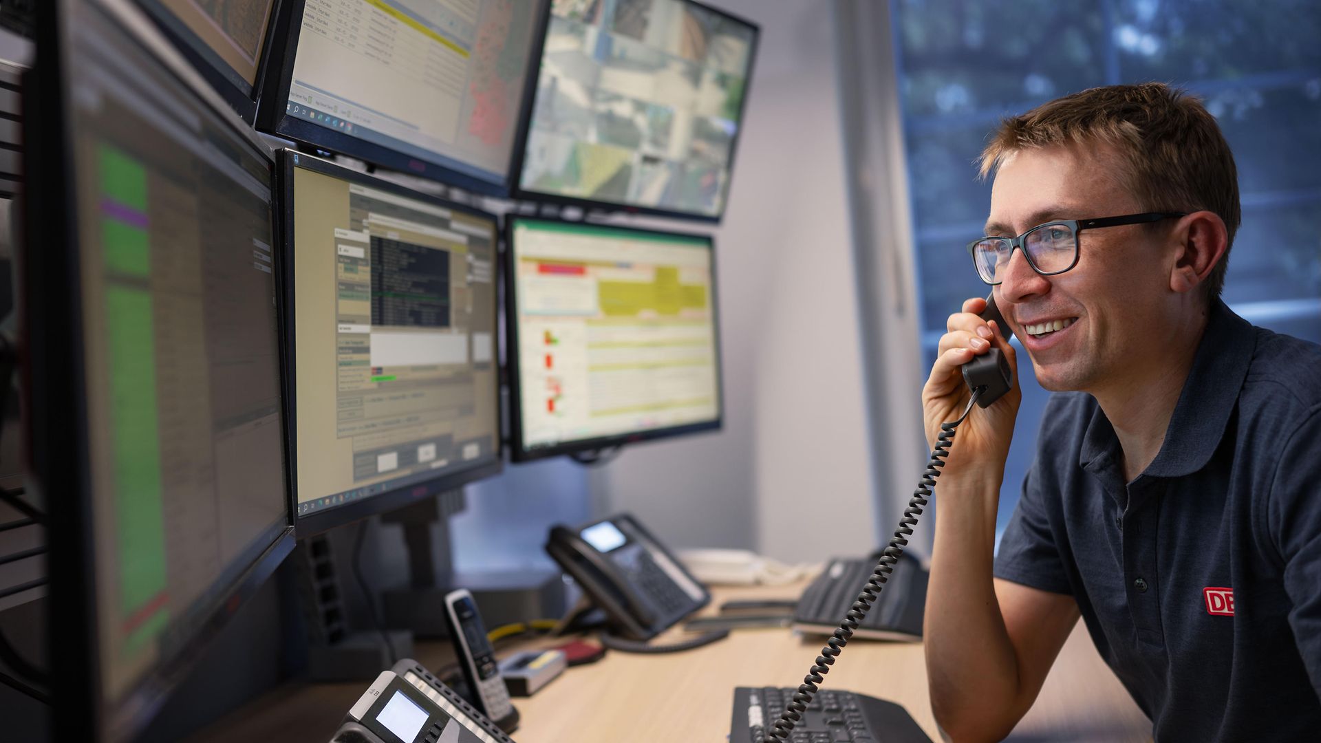 Mann am Telefon vor Bildschirmen