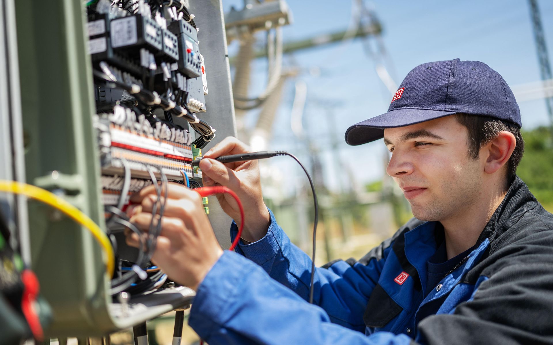 Mann mit Messgeräten in der Hand am Schaltkasten