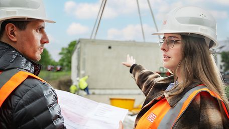 Frau mit Helm im Gespräch auf Baustelle
