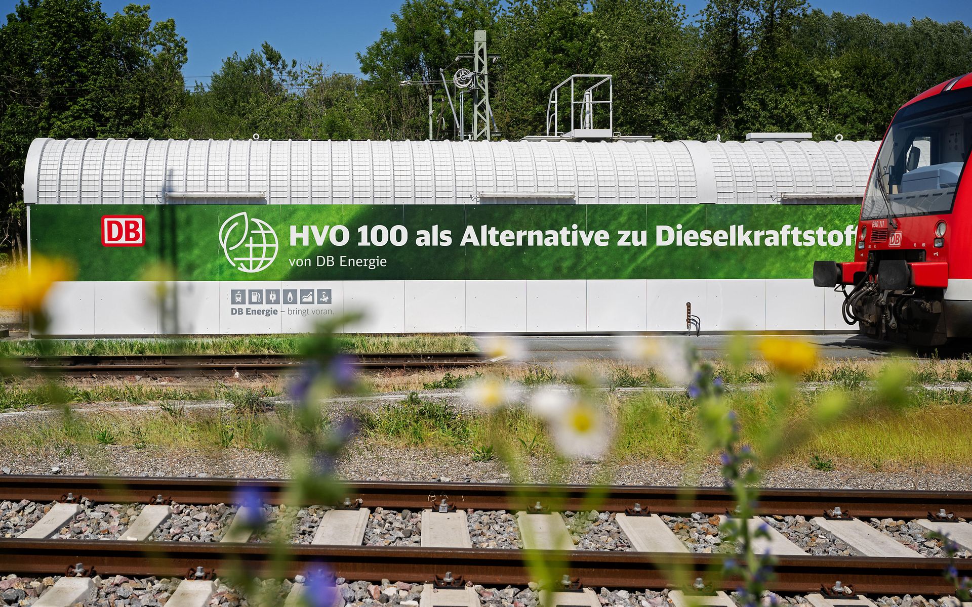Anlage für den alternativen Kraftstoff HVO 100 von DB Energie neben einem Regionalzug.