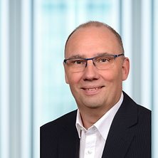Mann mit Anzug und Hemd lächelt in die Kamera