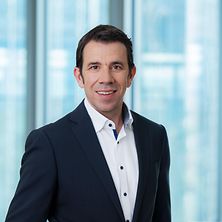Mann mit Anzug und Hemd lächelt in Kamera