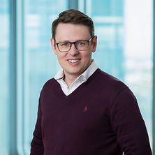 Mann mit Brille und Hemd lächelt in Kamera