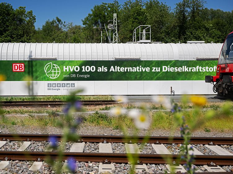 HVO-100-Tankanlage von DB Energie an einer Bahnanlage mit Gleisen und rotem Triebwagen.