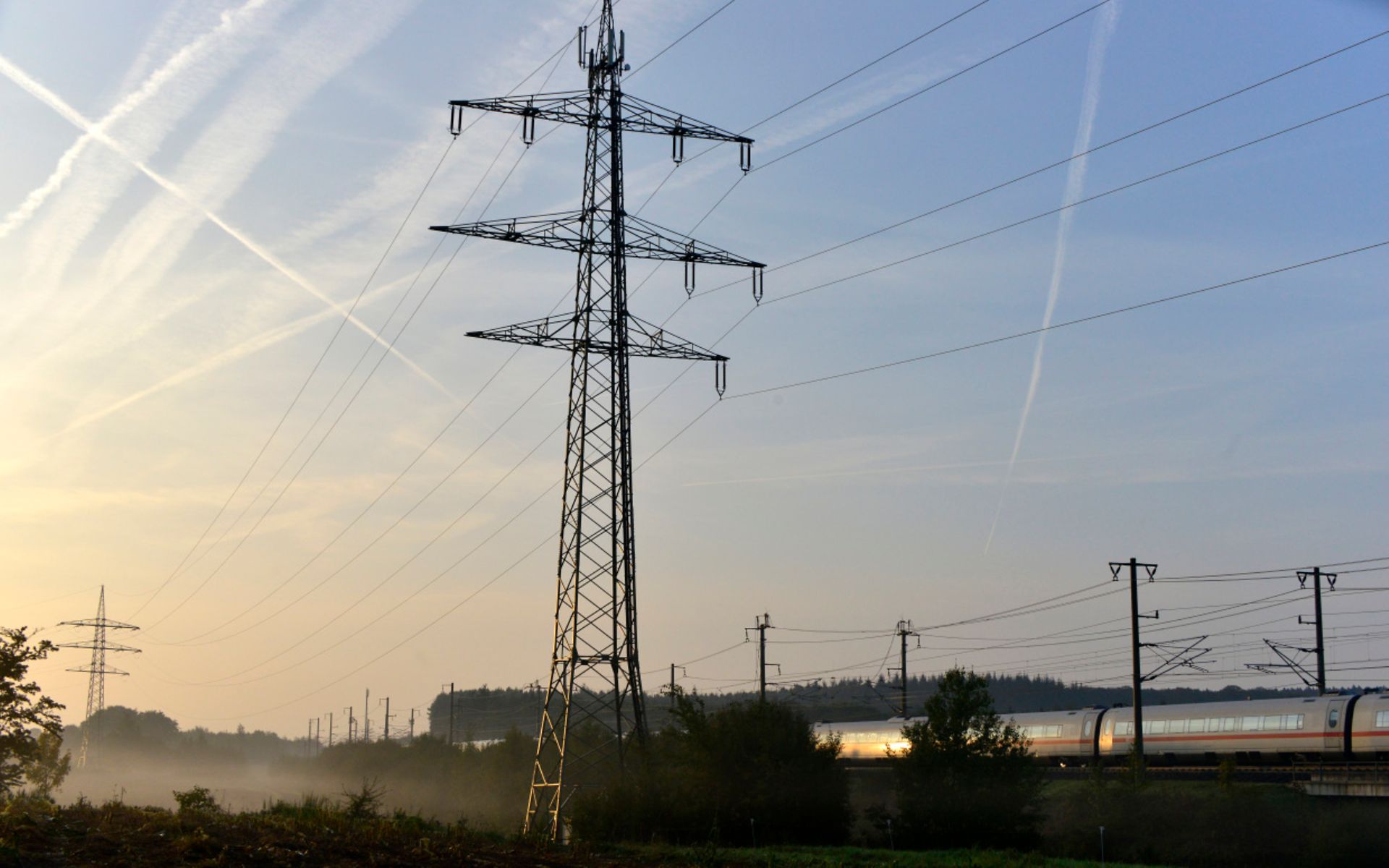 Bahnstrommast in Landschaft mit ICE