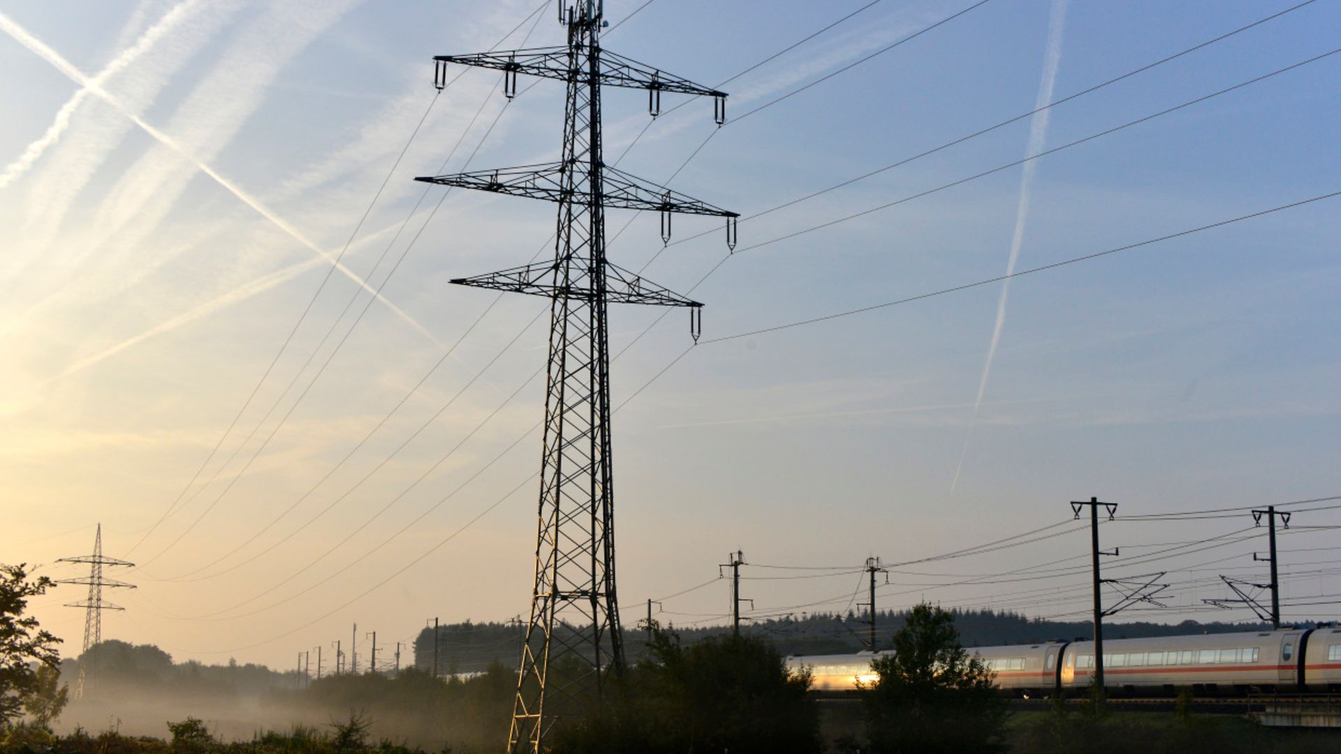 Bahnstrommast in Landschaft mit ICE