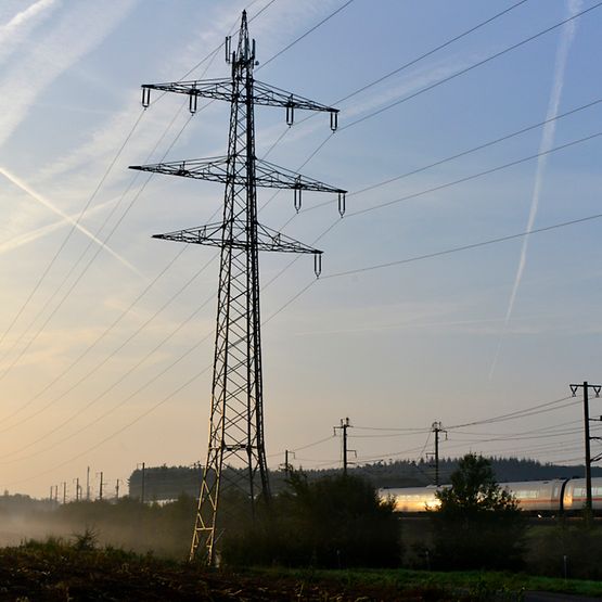 Bahnstrommast in Landschaft mit ICE