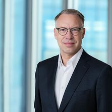 Mann mit Anzug und Hemd lächelt in die Kamera