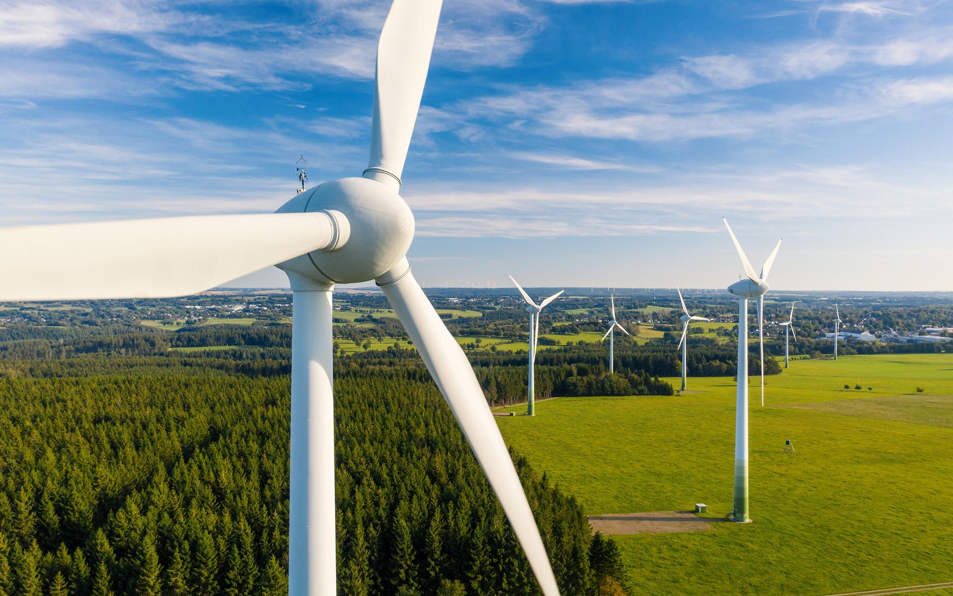 Windkraftanlage in grüner Landschaft mit blauem Himmel