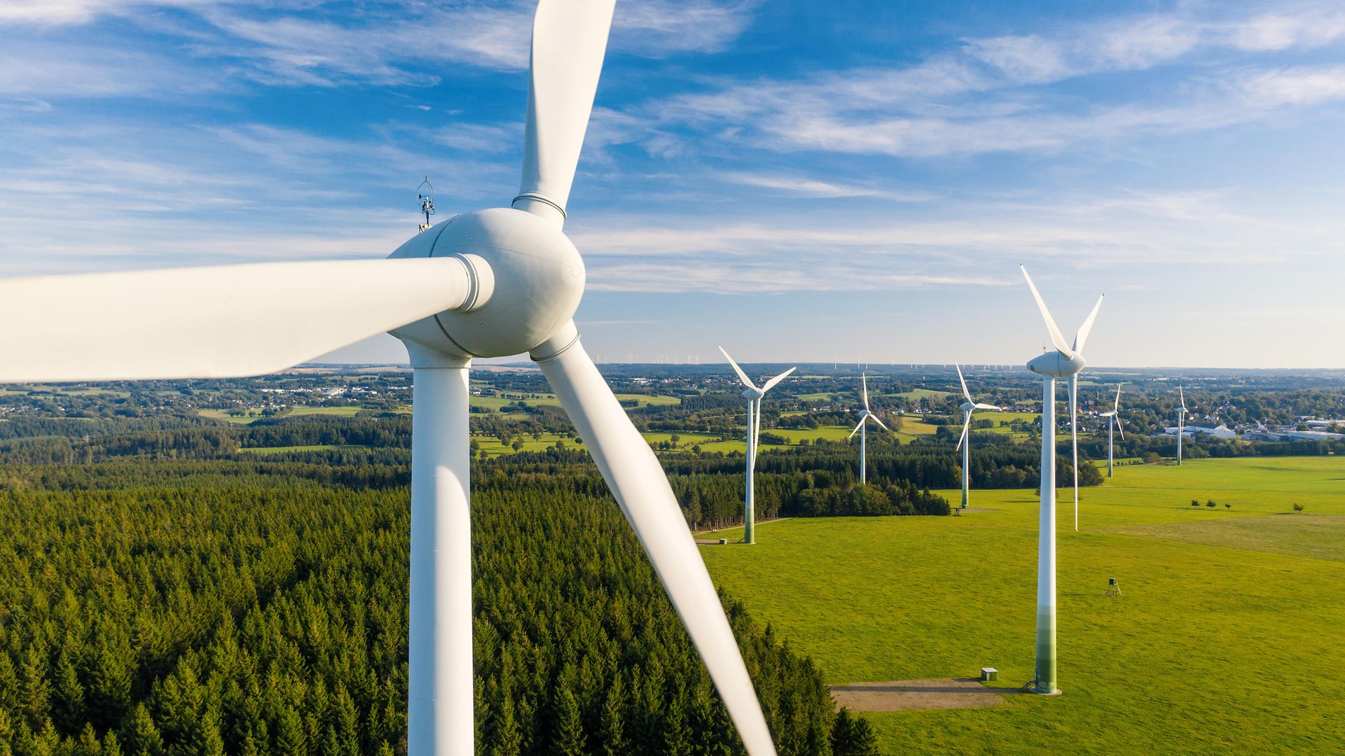 Windkraftanlage in grüner Landschaft mit blauem Himmel